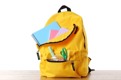 Photo of Backpack with different school stationery on wooden table against white background