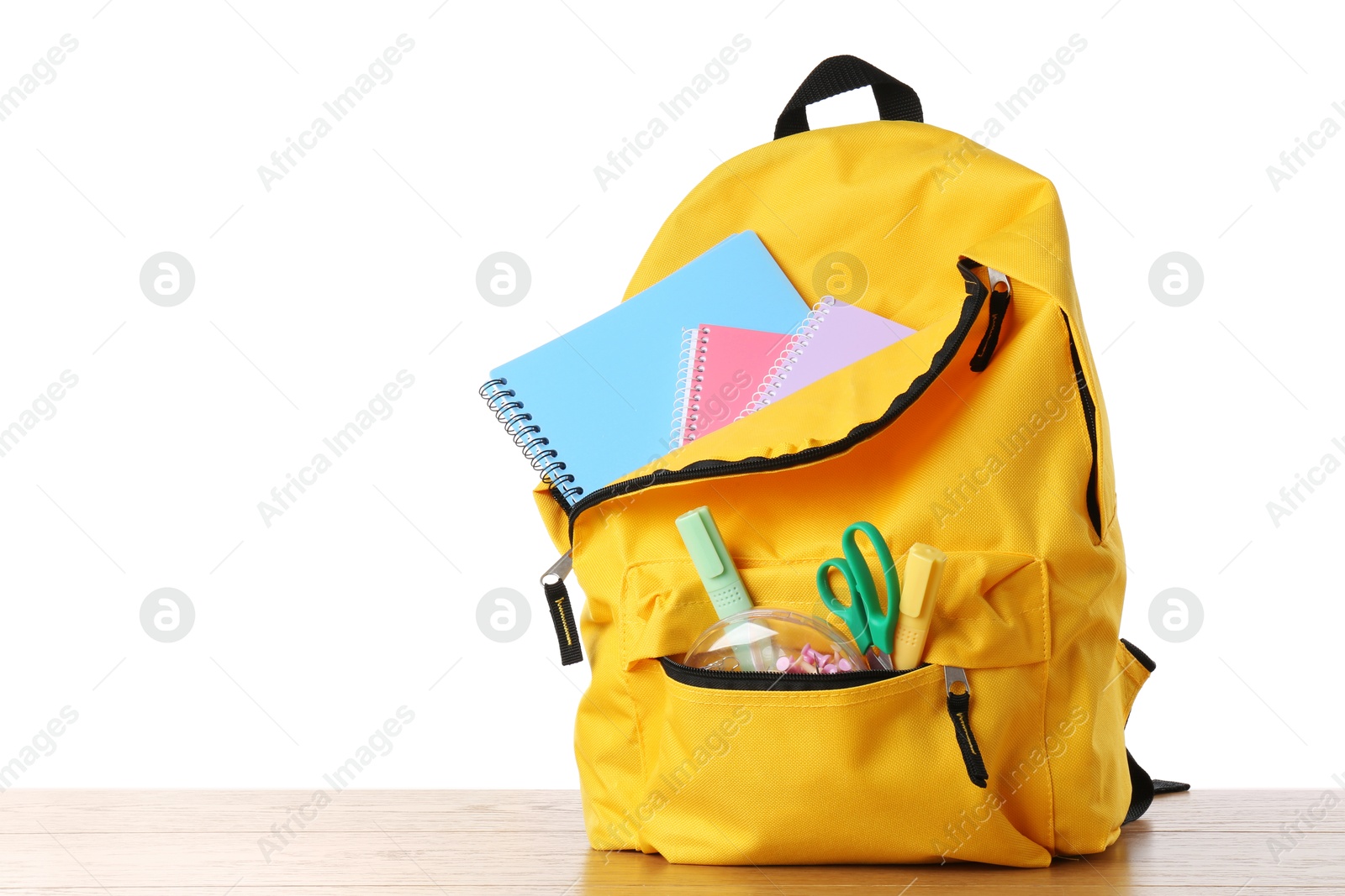 Photo of Backpack with different school stationery on wooden table against white background, space for text