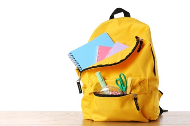 Photo of Backpack with different school stationery on wooden table against white background, space for text