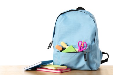 Photo of Backpack with different school stationery on wooden table against white background