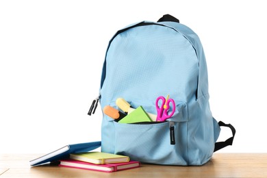 Photo of Backpack with different school stationery on wooden table against white background