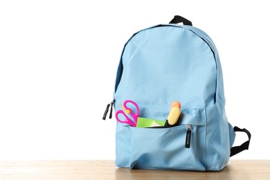 Photo of Backpack with different school stationery on wooden table against white background, space for text