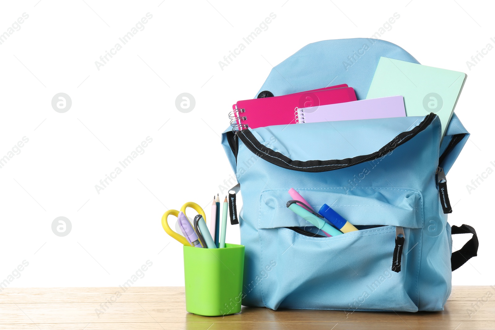 Photo of Backpack with different school stationery on wooden table against white background, space for text