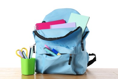 Photo of Backpack with different school stationery on wooden table against white background