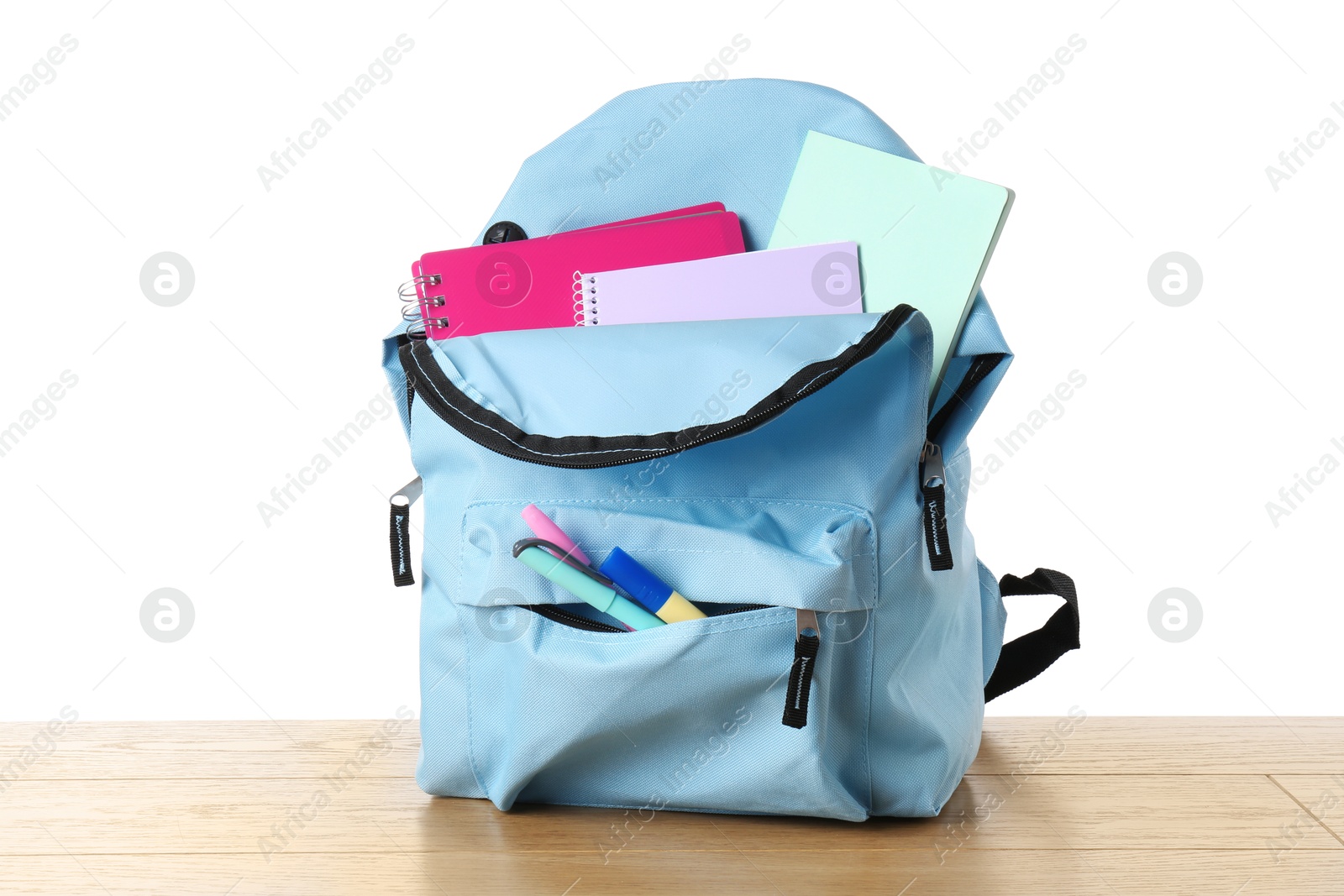 Photo of Backpack with different school stationery on wooden table against white background