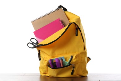 Photo of Backpack with different school stationery on wooden table against white background