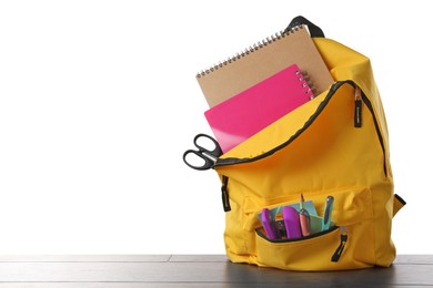 Photo of Backpack with different school stationery on wooden table against white background, space for text