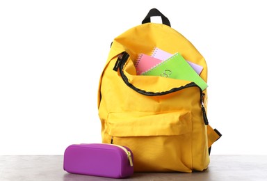 Photo of Backpack with different school stationery on gray textured table against white background