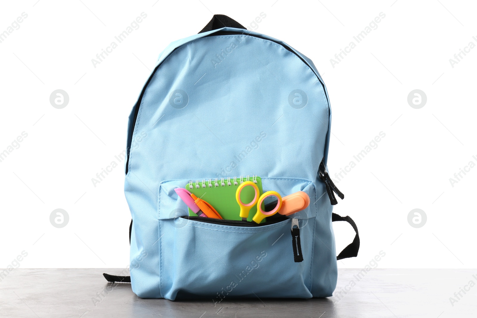 Photo of Backpack with different school stationery on gray textured table against white background