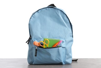 Photo of Backpack with different school stationery on gray textured table against white background