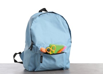 Photo of Backpack with different school stationery on gray textured table against white background