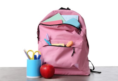 Photo of Backpack with different school stationery and apple on gray textured table against white background