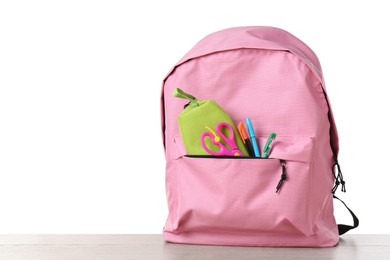 Photo of Backpack with different school stationery on wooden table against white background, space for text