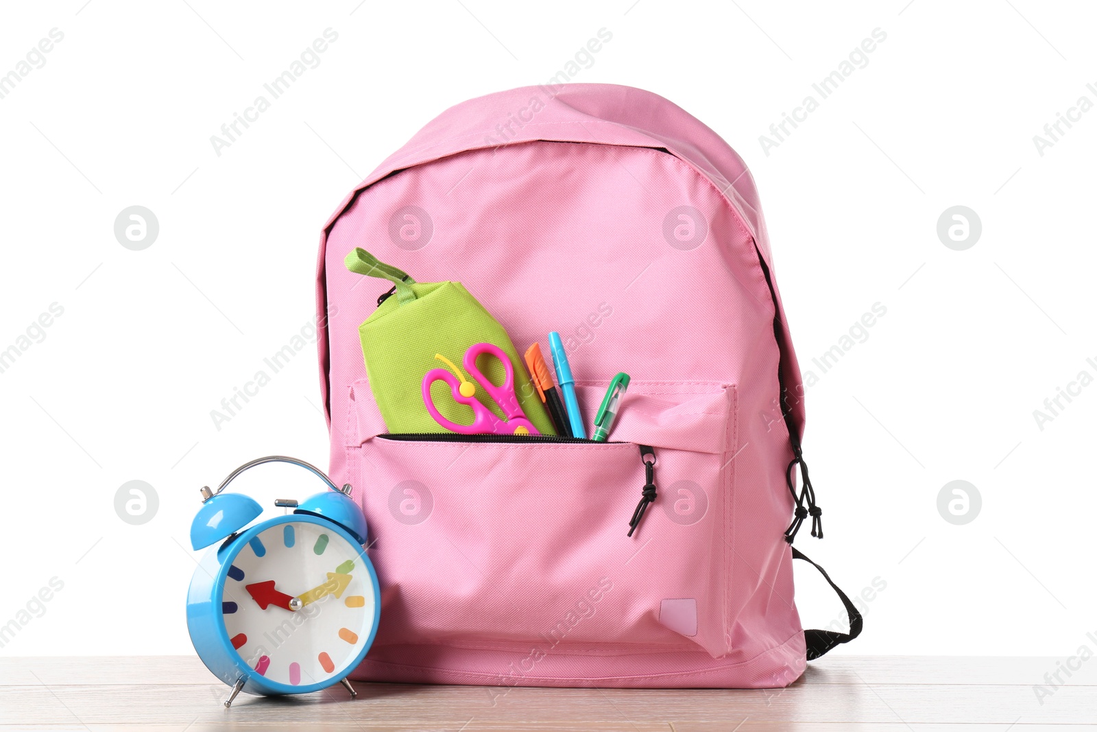 Photo of Backpack with different school stationery and alarm clock on wooden table against white background