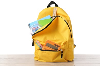 Photo of Backpack with different school stationery on wooden table against white background