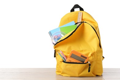 Photo of Backpack with different school stationery on wooden table against white background, space for text