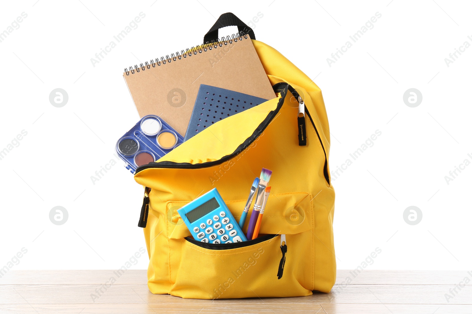 Photo of Backpack with different school stationery on wooden table against white background