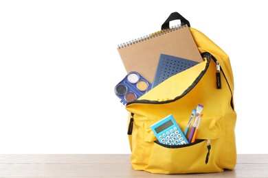 Photo of Backpack with different school stationery on wooden table against white background, space for text