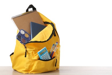 Photo of Backpack with different school stationery on wooden table against white background, space for text