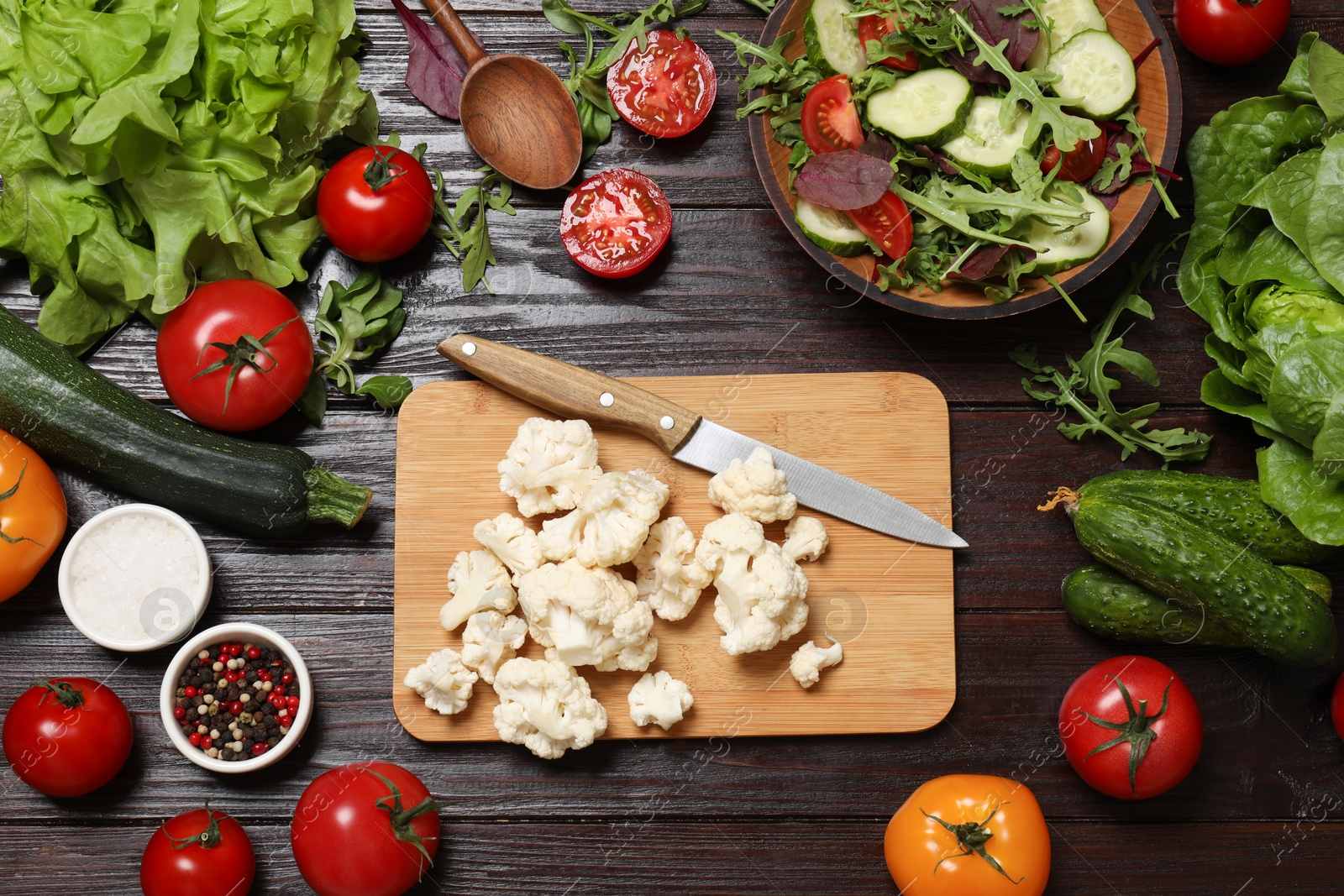 Photo of Healthy vegetarian food. Pieces of cauliflower, salad, peppercorns and vegetables on wooden table, flat lay