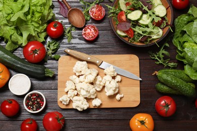 Healthy vegetarian food. Pieces of cauliflower, salad, peppercorns and vegetables on wooden table, flat lay