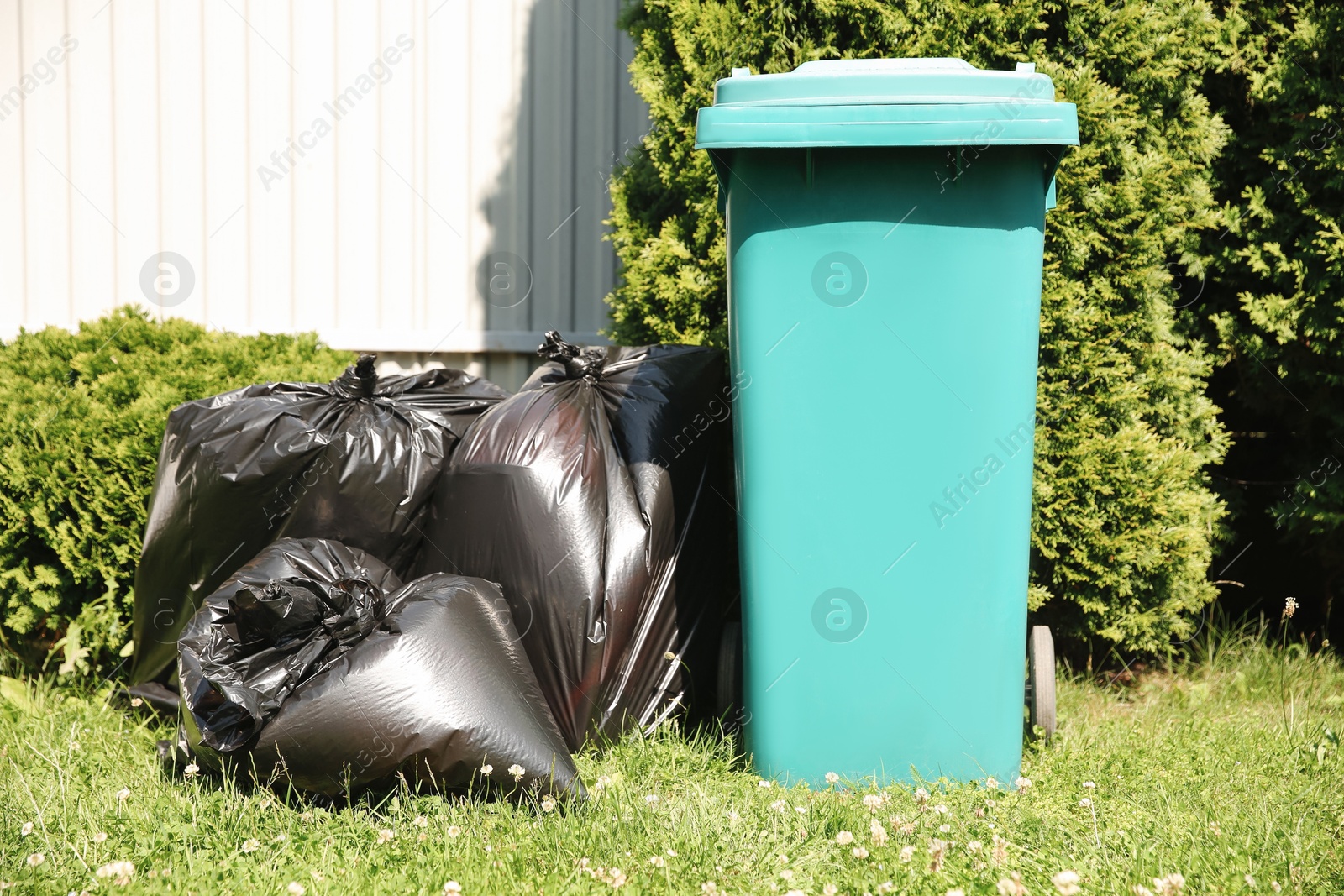 Photo of Trash bags full of garbage near bin outdoors