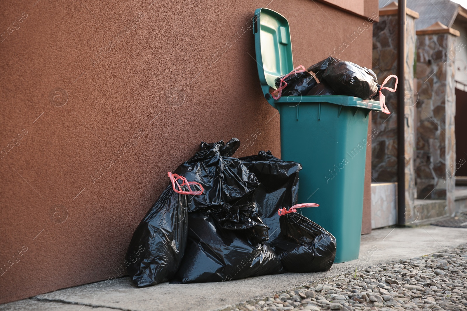 Photo of Trash bags full of garbage near bin outdoors