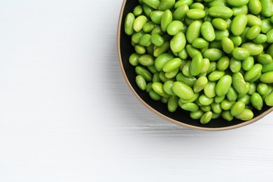 Fresh edamame soybeans in bowl on white wooden table, top view. Space for text