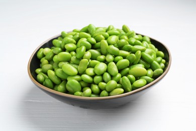 Fresh edamame soybeans in bowl on white wooden table, closeup