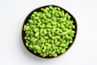 Fresh edamame soybeans in bowl on white wooden table, top view