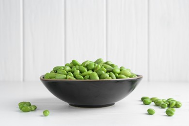 Photo of Fresh edamame soybeans in bowl on white wooden table, closeup