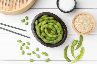 Fresh edamame pods, soybeans, salt and seeds on white wooden table, flat lay