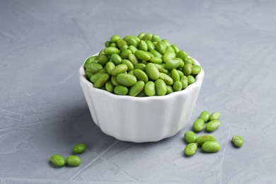 Photo of Fresh edamame soybeans in bowl on grey textured table, closeup