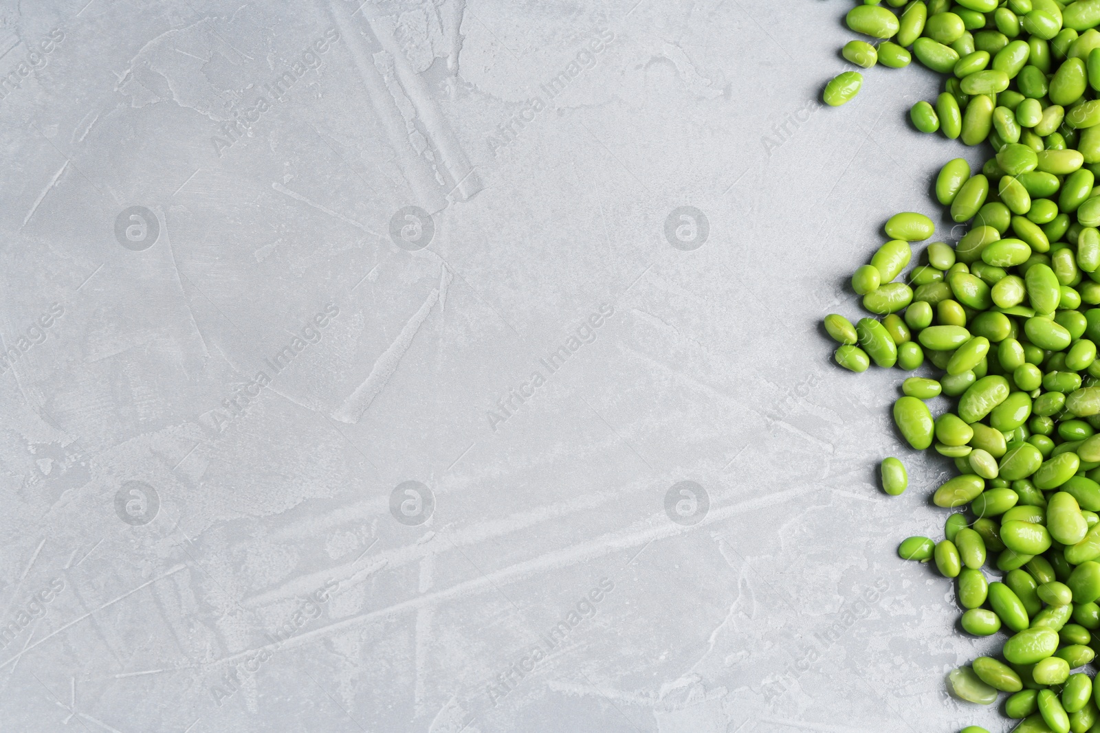 Photo of Fresh edamame soybeans on grey textured table, top view. Space for text