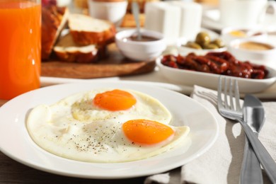 Photo of Tasty breakfast. Fried eggs, orange juice and cutlery on table, closeup