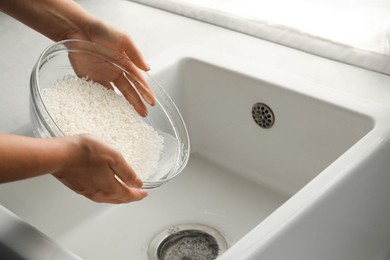 Photo of Woman rinsing rice in bowl above sink, closeup