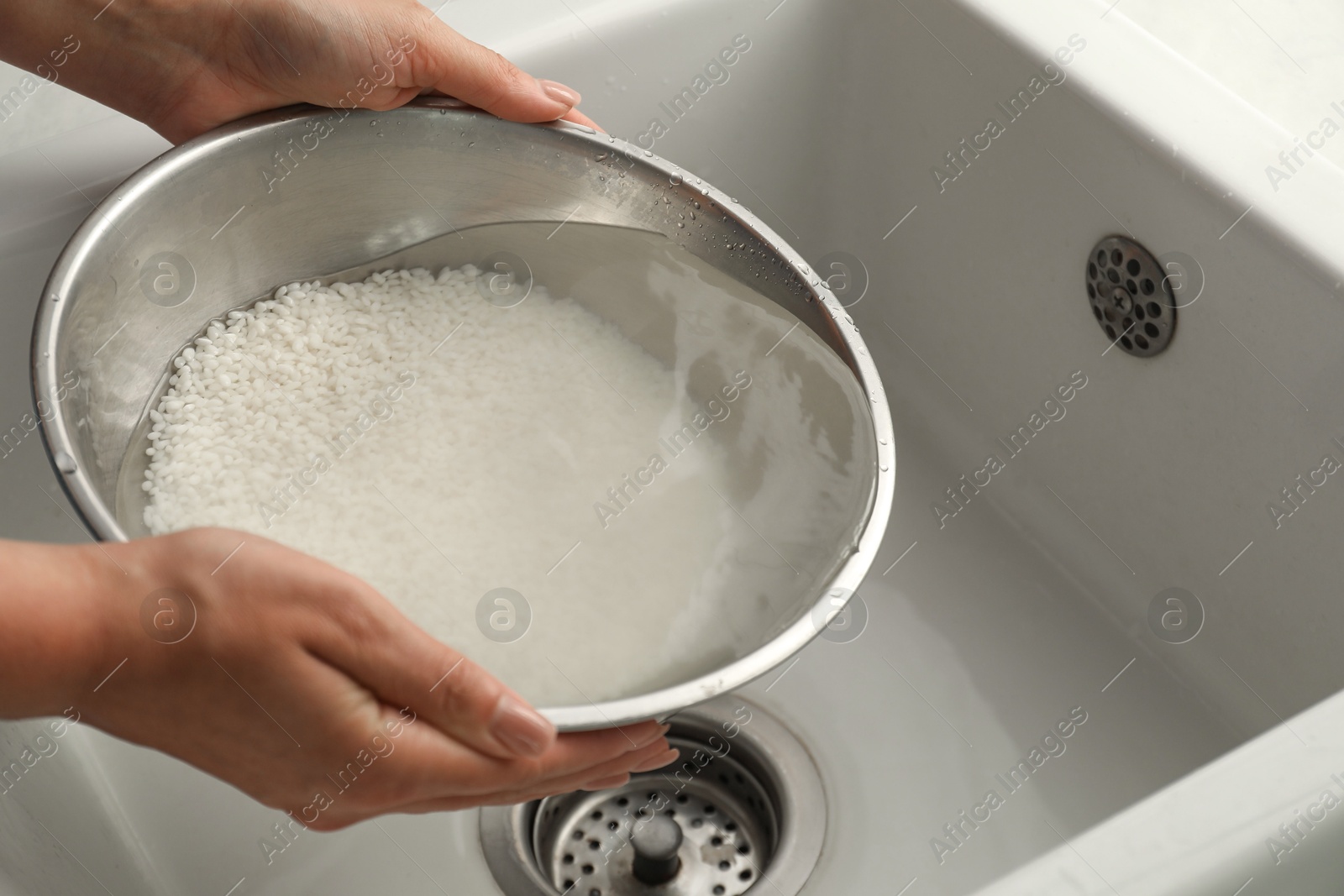 Photo of Woman rinsing rice in bowl above sink, closeup