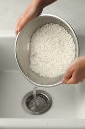 Photo of Woman rinsing rice in bowl above sink, closeup