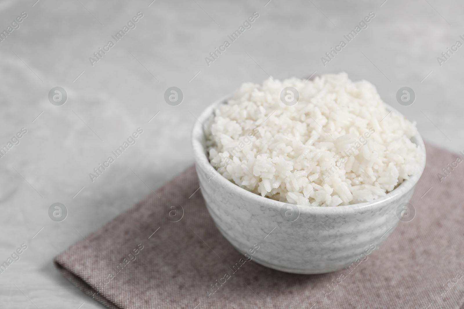 Photo of Delicious boiled rice in bowl on grey table. Space for text