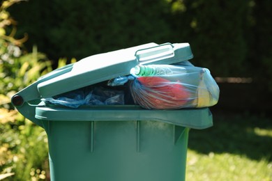 Photo of Trash bags in garbage bin outdoors, closeup