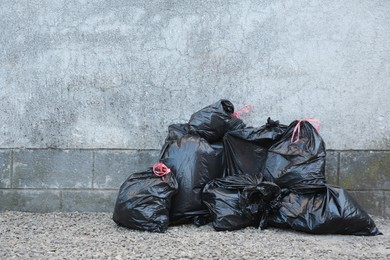 Photo of Many trash bags with garbage near wall outdoors