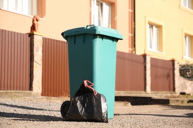 Photo of Trash bag full of garbage near bin outdoors