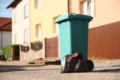 Photo of Trash bag full of garbage near bin outdoors