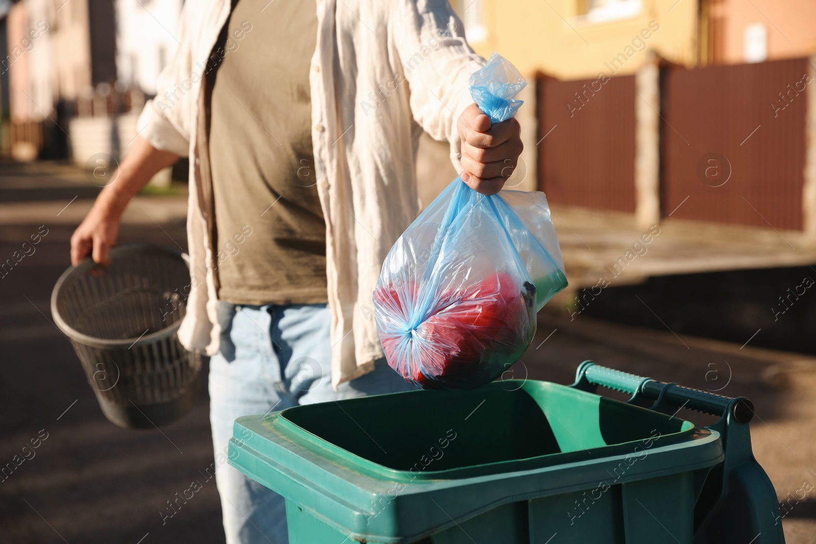 Photo of Man throwing trash bag into bin outdoors, closeup