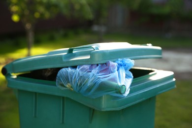 Photo of Trash bags full of garbage in bin outdoors, closeup