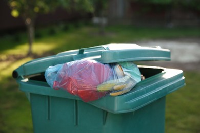 Photo of Trash bags full of garbage in bin outdoors, closeup