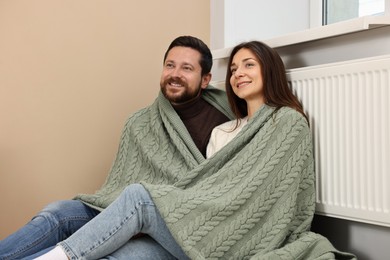 Photo of Happy couple near heating radiator at home