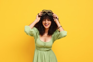 Photo of Smiling young woman with carnival mask on yellow background