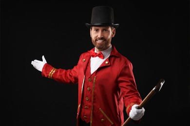 Portrait of showman in red costume and hat on black background