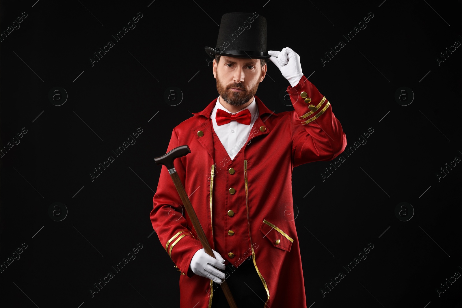 Photo of Portrait of showman in red costume and hat on black background